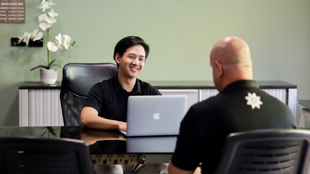 Clinical team member and a client in conversation across a desk at a Chiang Mai rehab
