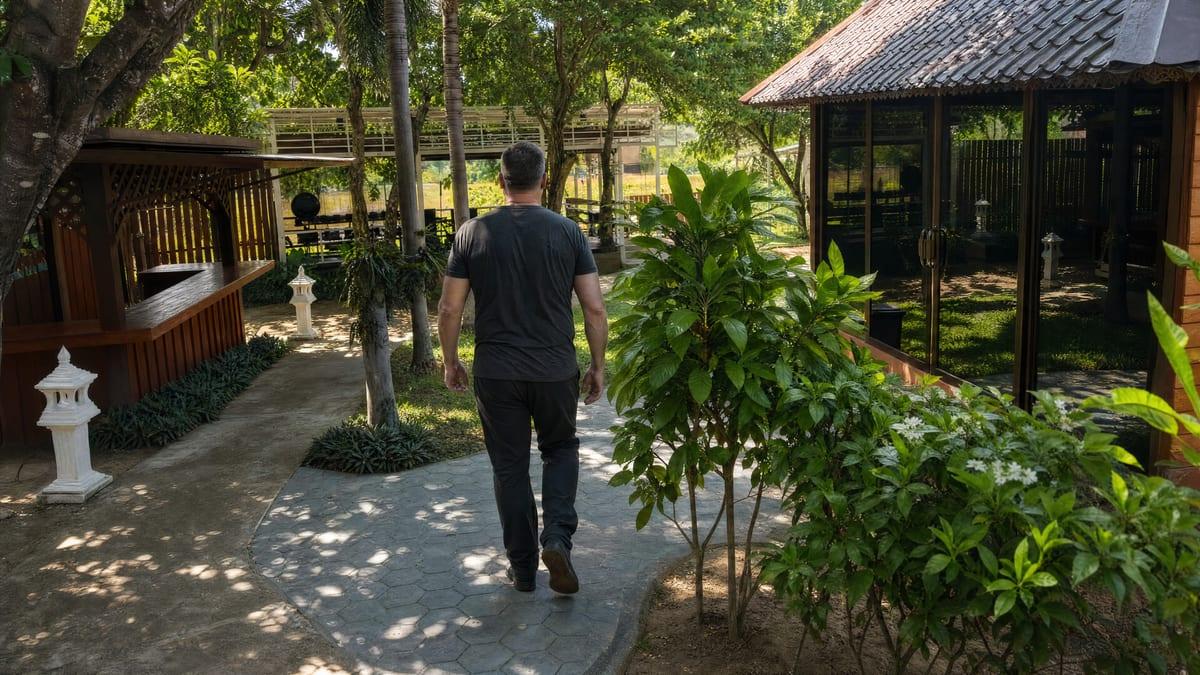 Man walking away down a garden stepping-stone path at a rehab in Chiang Mai