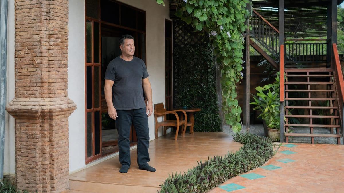 Man standing on a timber veranda deck looking out across a courtyard at a Chiang Mai rehab