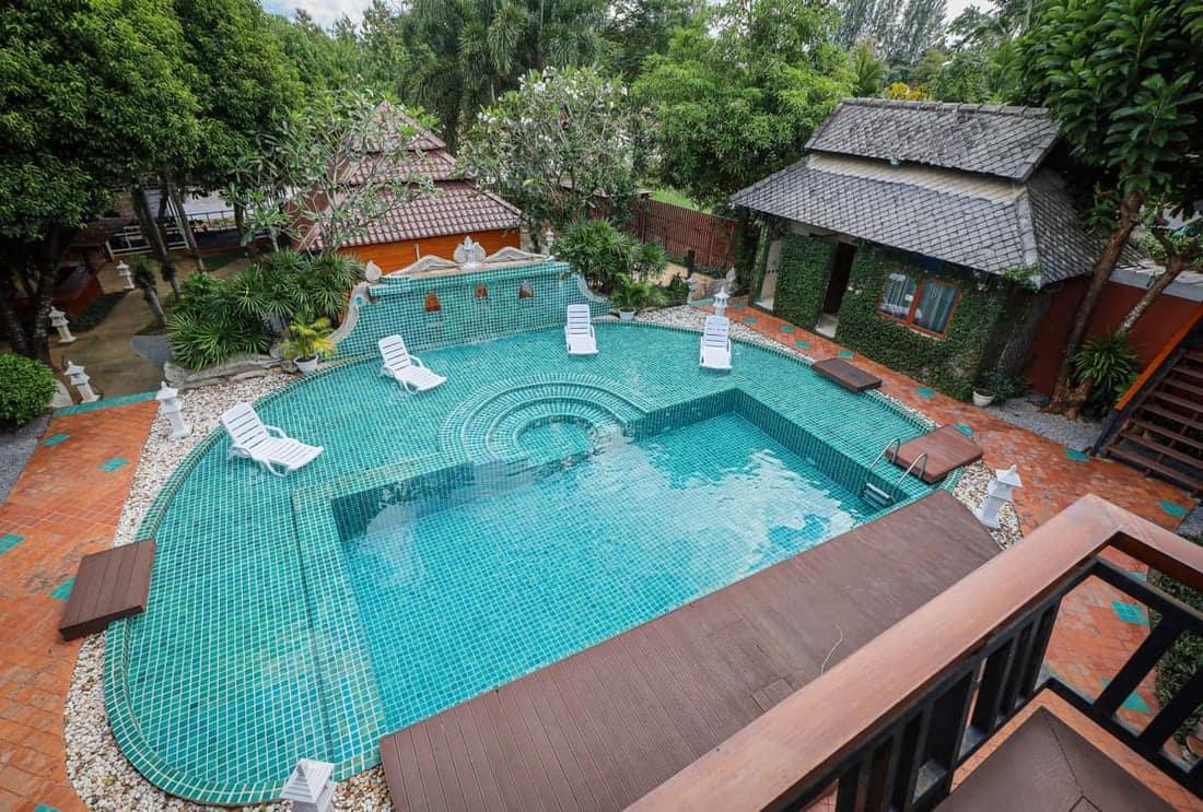 Elevated view of teal pool with Lanna buildings and tropical gardens at Jintara Rehab addiction treatment Chiang Mai