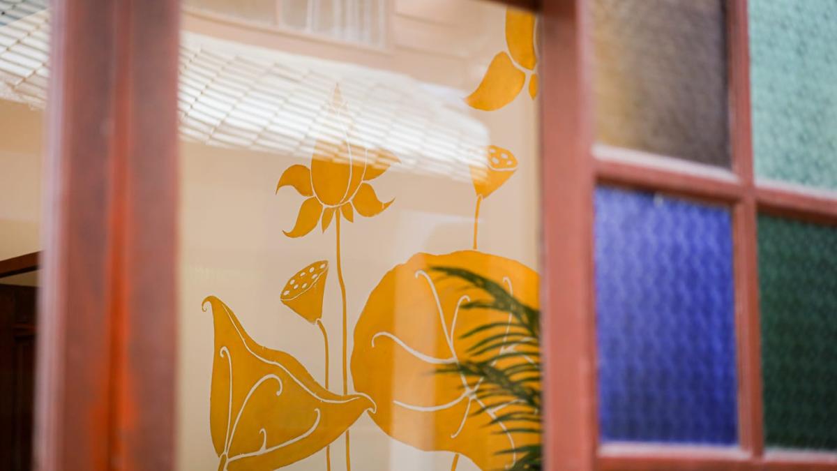 Hand-painted lotus panel in a timber window frame at a residential rehab in Chiang Mai