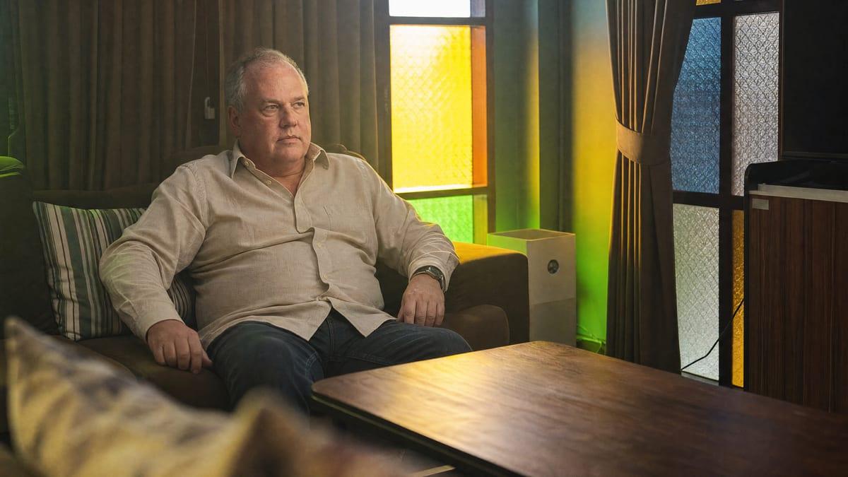 A man sits quietly in a warm stained-glass lounge at a private Chiang Mai rehab