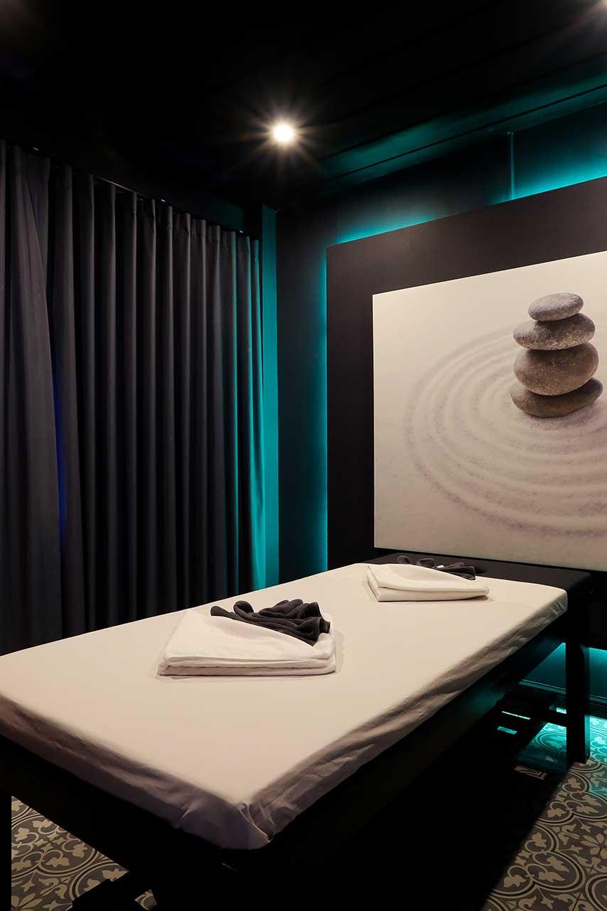 Private massage room with teal lighting and zen artwork at Jintara Rehab Thailand