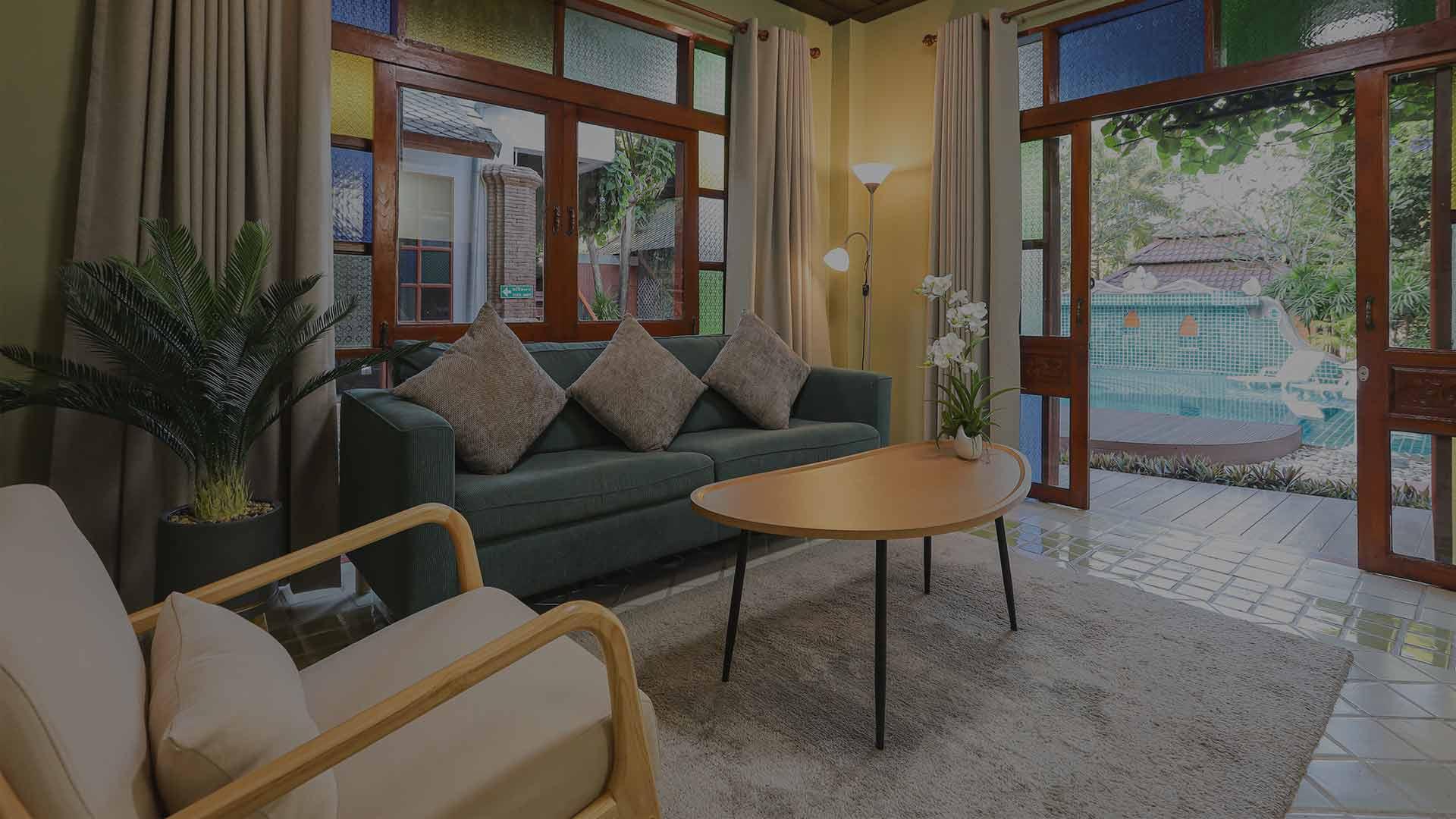 Poolside lounge with teal sofa and open doors to pool at Jintara Rehab Thailand