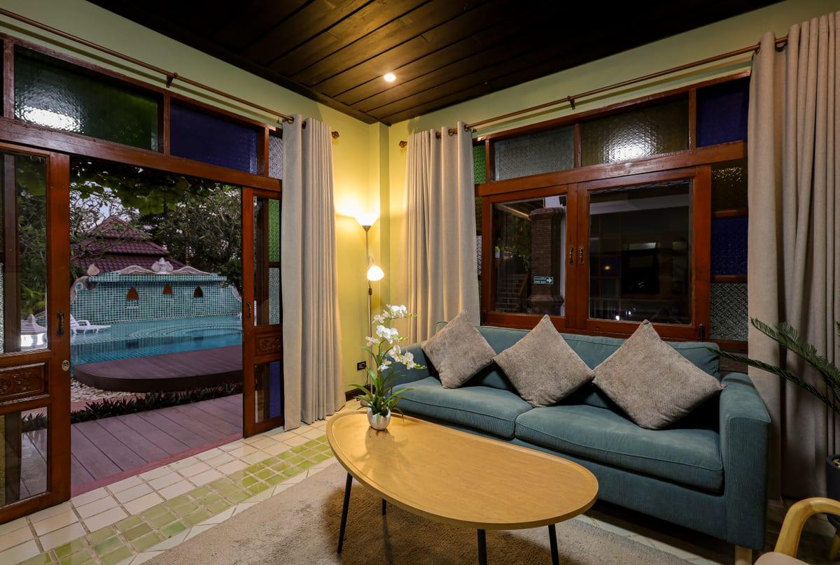 Evening interior lounge with teal sofa and pool doors open at Jintara private rehab Chiang Mai