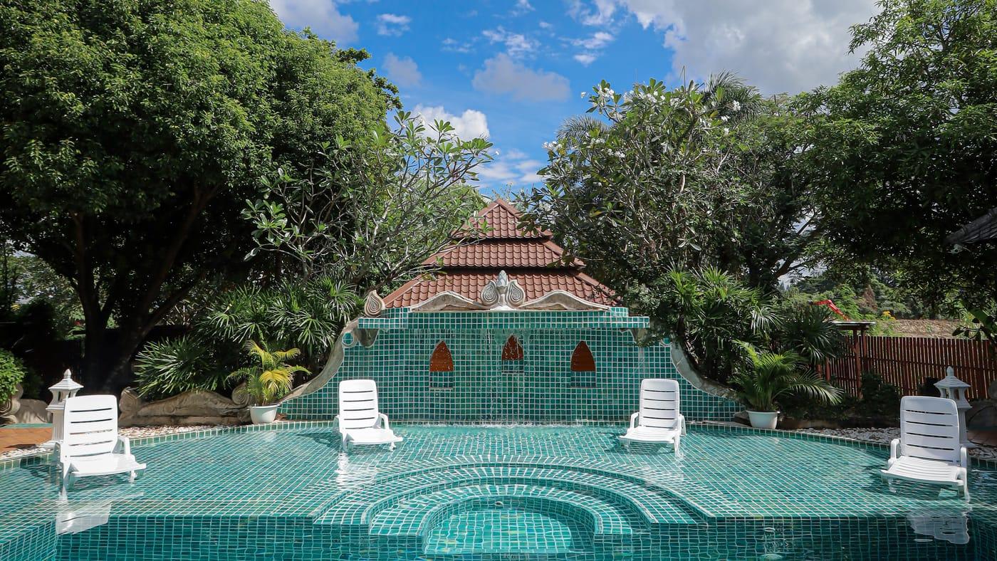 A tiled pool with sun loungers in front of a fountain wall at Jintara Rehab in Chiang Mai
