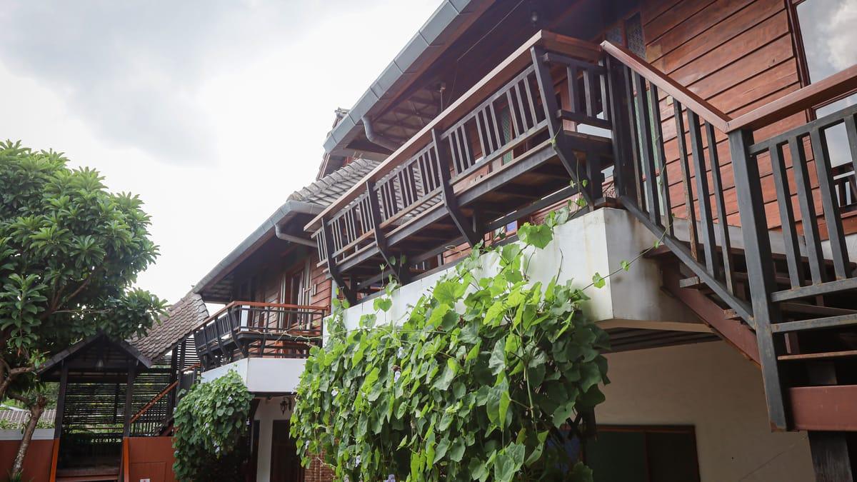 Teak building with wooden balconies and climbing vines at Jintara Rehab in Chiang Mai