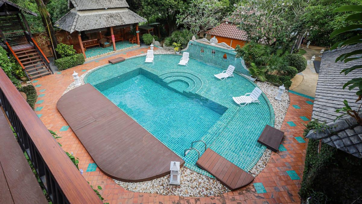 Pool, sala and teak buildings seen from a balcony at Jintara Rehab in Chiang Mai