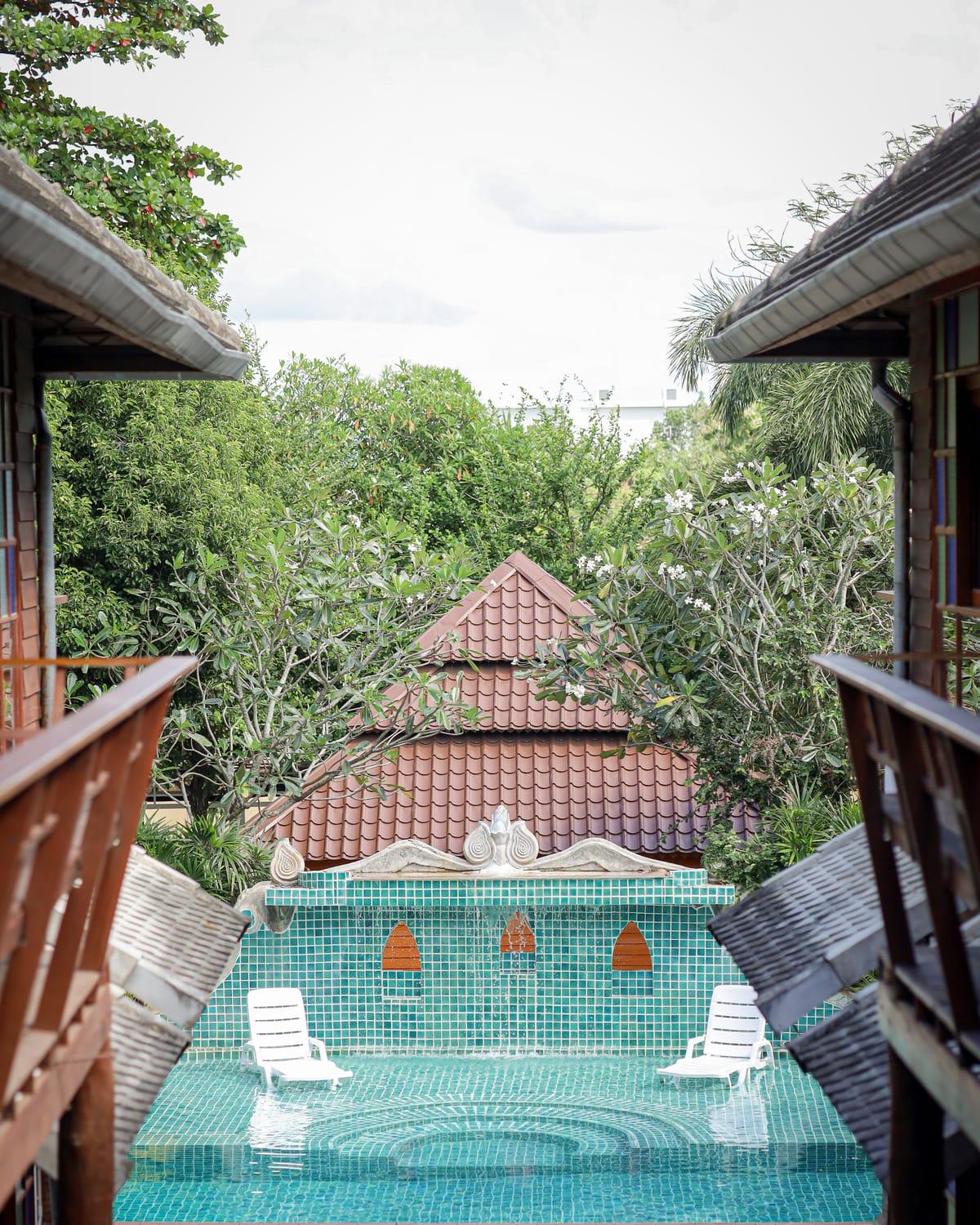 Two white loungers in the pool below the tiled fountain wall at Jintara Rehab in Chiang Mai