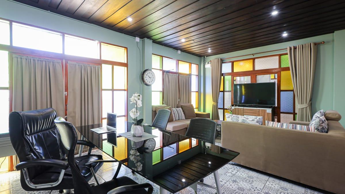 Shared lounge with sofas, a desk and stained-glass windows at Jintara Rehab in Chiang Mai