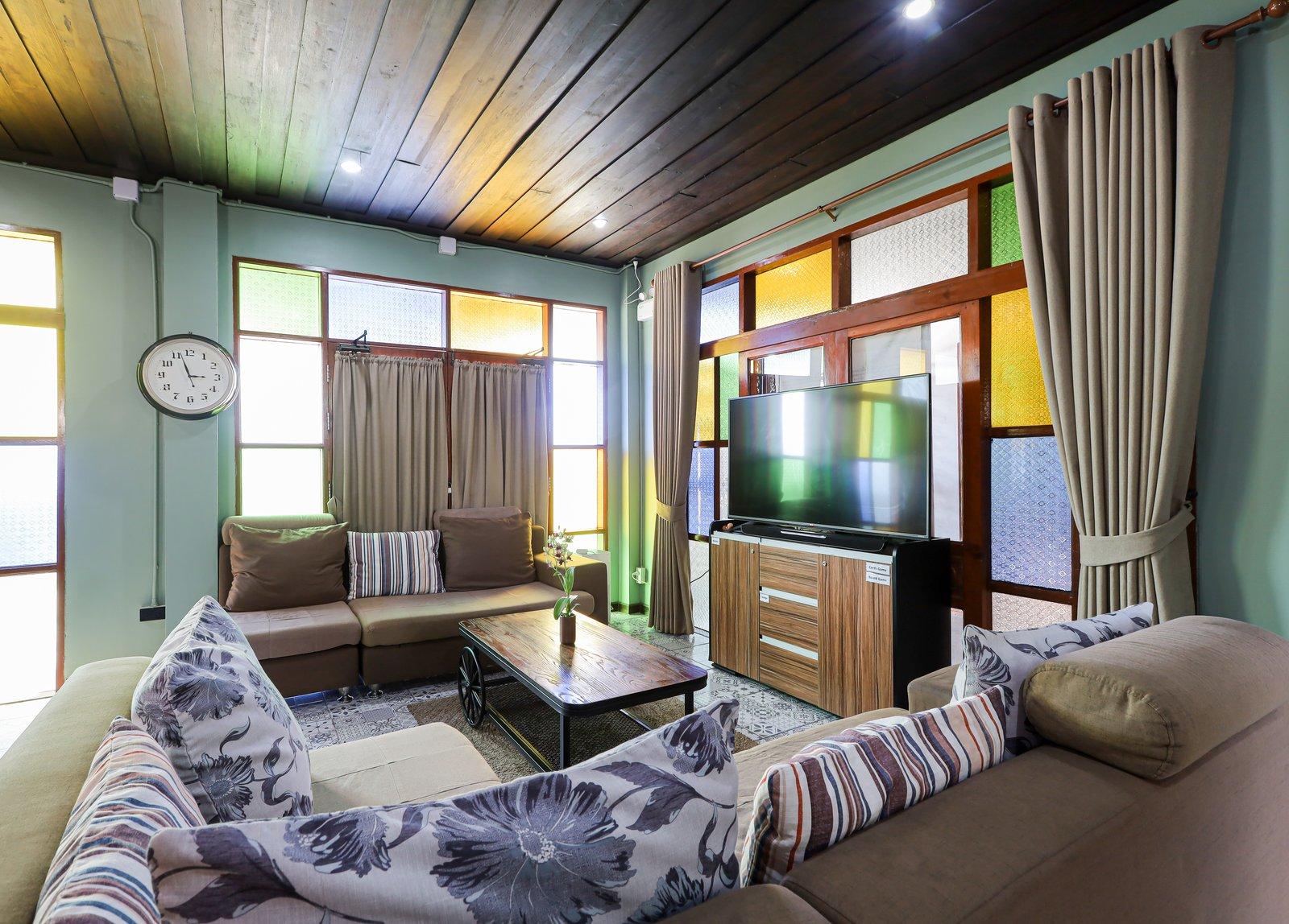 A sitting room at Jintara Rehab in Chiang Mai with sofas, a coffee table, and stained-glass windows