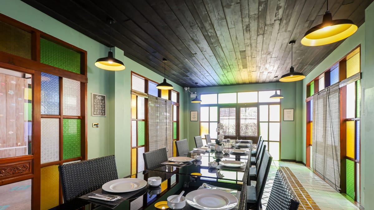 Dining room with a long glass table set with plates and cups at Jintara Rehab