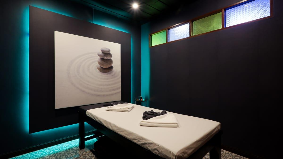 A massage table in a treatment room with a stone painting and stained-glass windows at Jintara Rehab in Chiang Mai