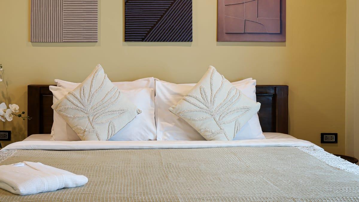 A made bed with white pillows and a folded robe in a bedroom at Jintara Rehab in Chiang Mai
