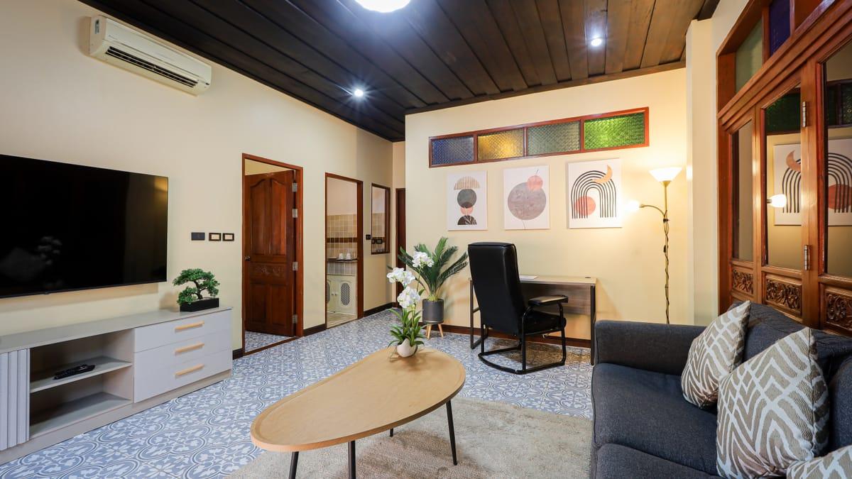 Sitting room with a desk, sofa and orchids at Jintara Rehab in Chiang Mai