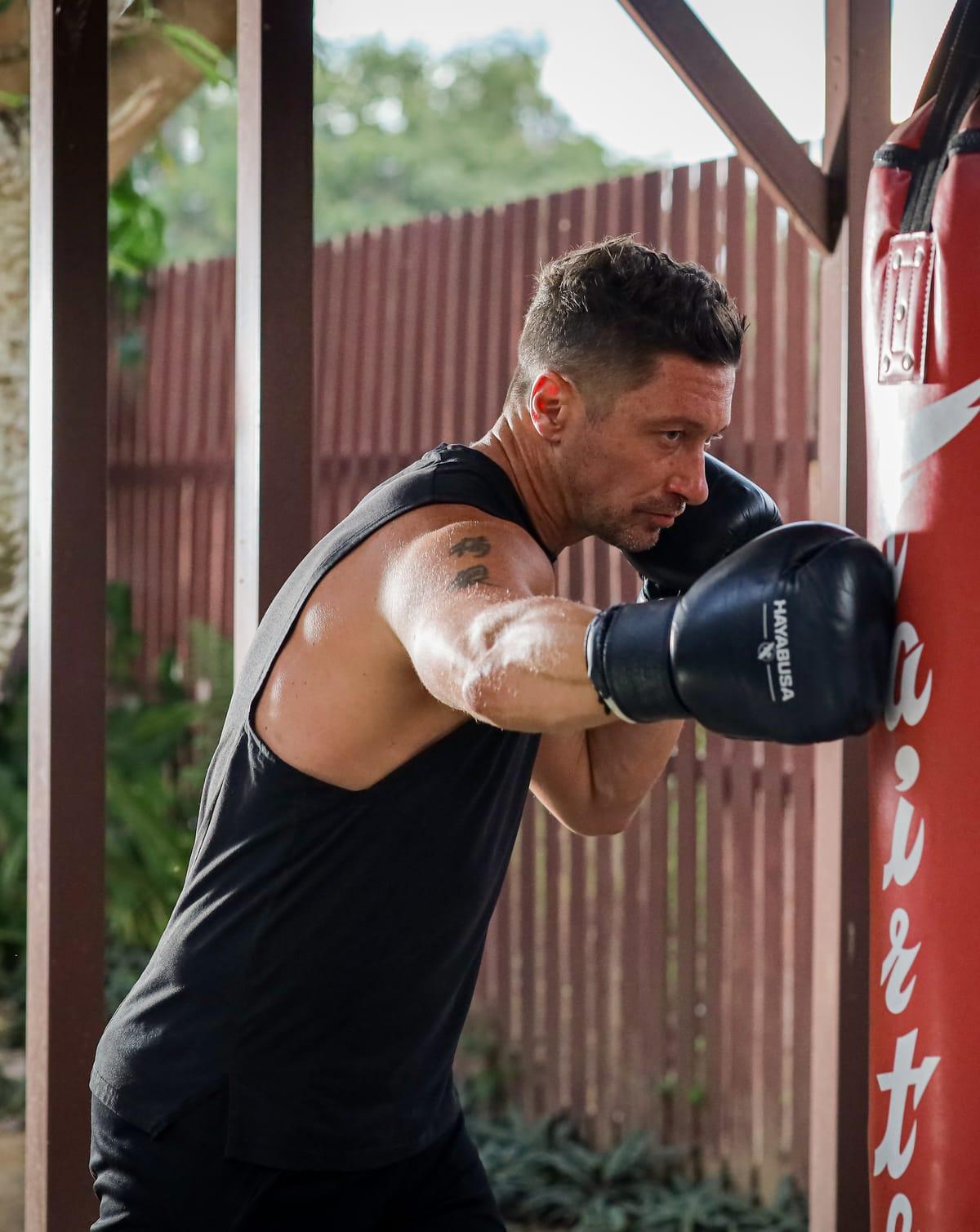 A man trains on a heavy bag in the garden at Jintara Rehab in Chiang Mai