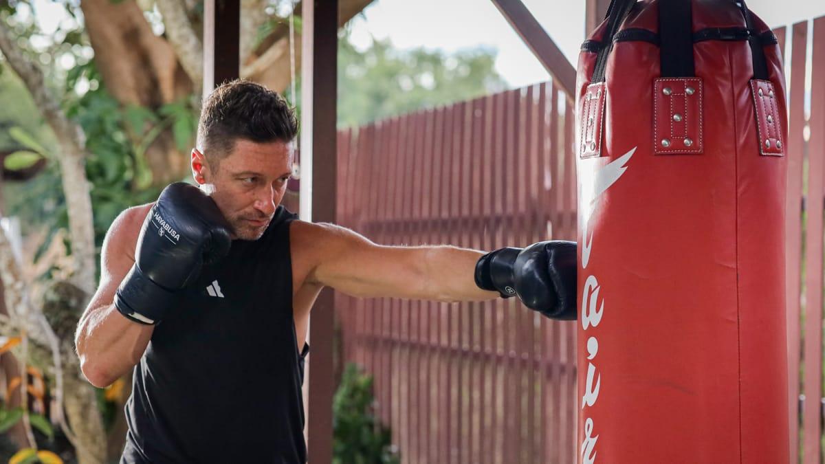 A man in boxing gloves working a heavy bag under the garden pavilion at Jintara Rehab in Chiang Mai