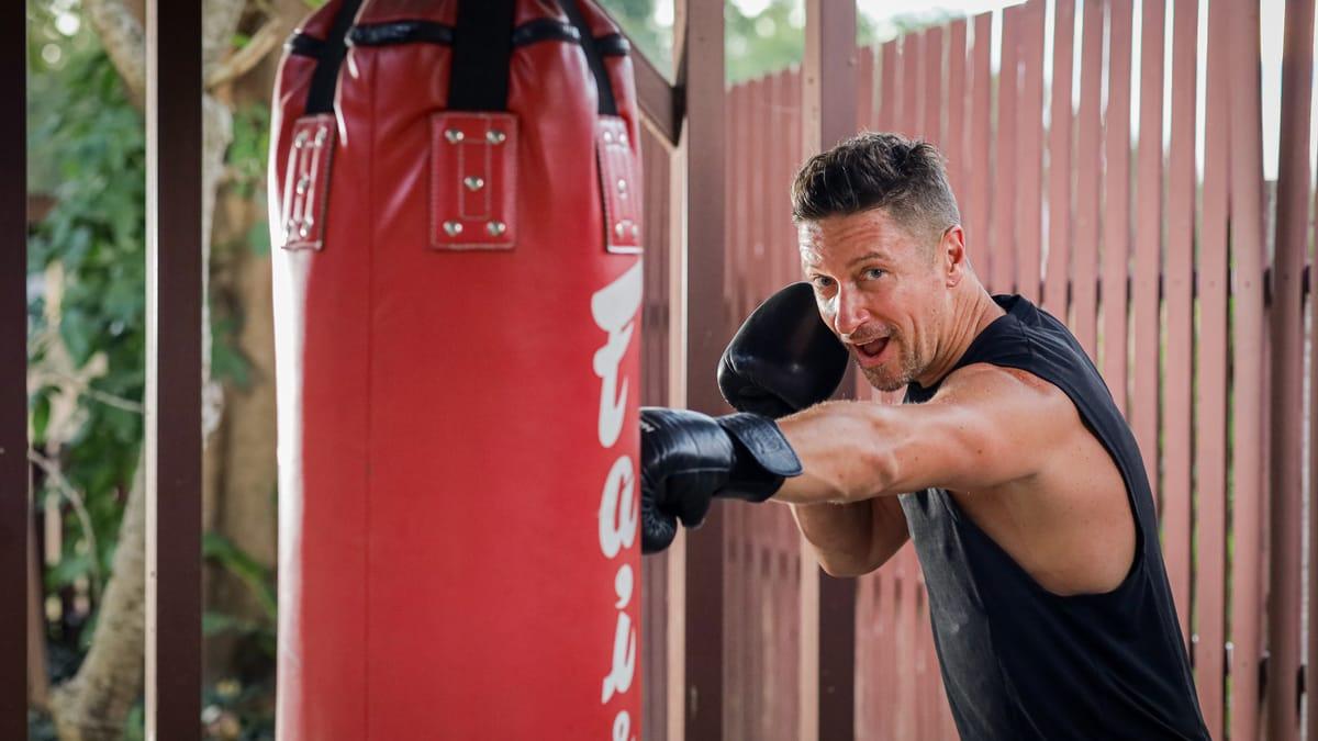 A man punches a heavy bag in the outdoor training area at Jintara Rehab in Chiang Mai