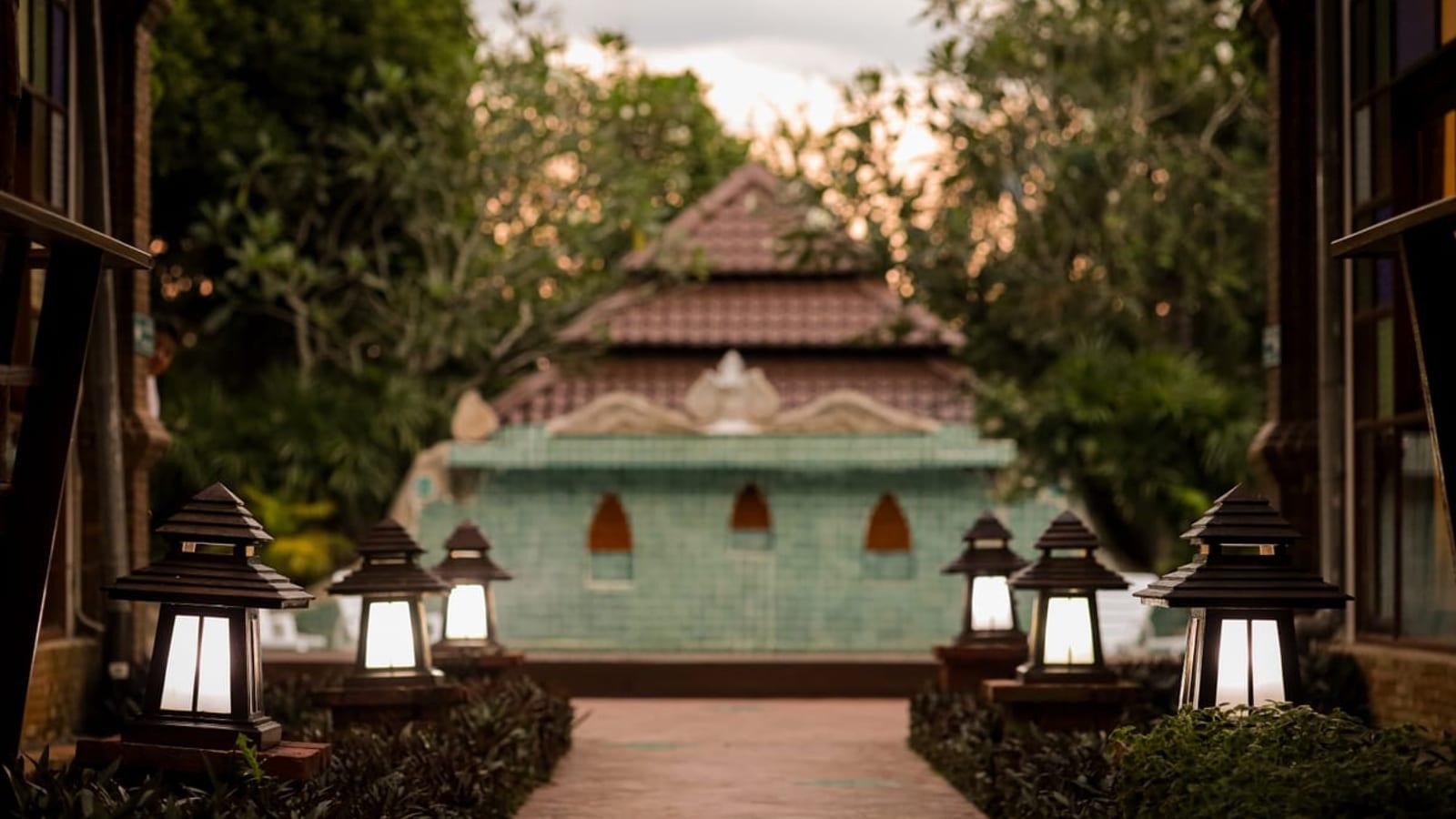 Lantern-lit walkway toward the water feature at Jintara Rehab in Chiang Mai at dusk
