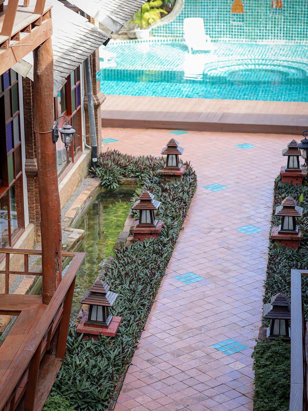 Lantern-lined brick pathway leading to the pool terrace at Jintara Rehab in Chiang Mai