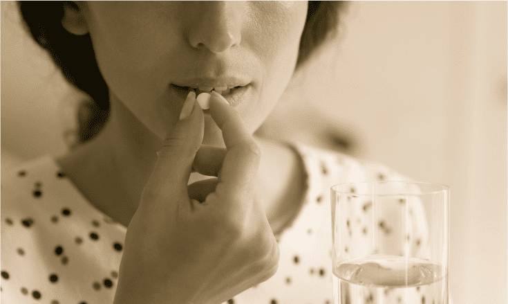 Person taking a pill with water, representing prescription medication addiction.